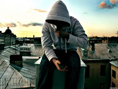 Мужчина со скрытым под капюшоном лицом сидит на крыше — Фотографии на аву